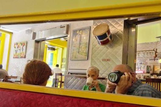 A man takes a photo in a mirror and captures a moment of eating at breakfast.