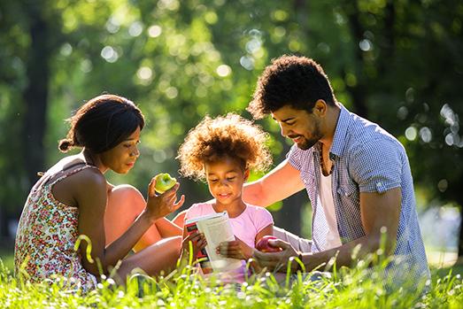 adults reading with a child outdoors