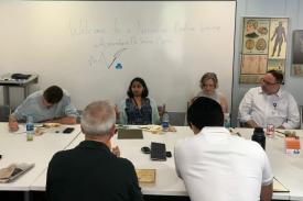 Sneha Mantri sits in the middle of the table with 5 participants surrounding her as she talks about Narrative Medicine. The whiteboard behind her says, &amp;quot;Welcome to a Narrative Medicine Workshop with neurolgist, Dr. Sneha Mantri.&amp;quot;