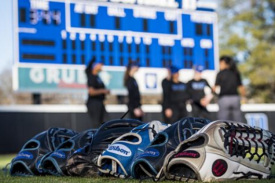 softball gloves in foreground, stadium and players out of focus