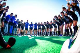 field hockey players & coaches in huddle
