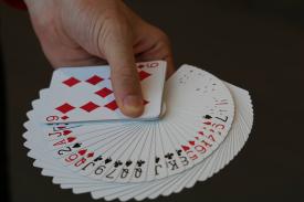 hand holding a deck of cards spread out showing each suit