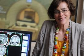 Marlene Behrmann, PhD, with images of brain scans on computer in the background