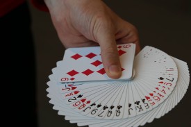 hand holding a deck of cards spread out showing each suit