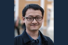 Junting Huang headshot, wearing a blue shirt and blazer and glasses
