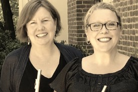 Sepia-toned photo of flutists Carla Copeland-Burns and Erinn Frechette standing in front of a brick building.