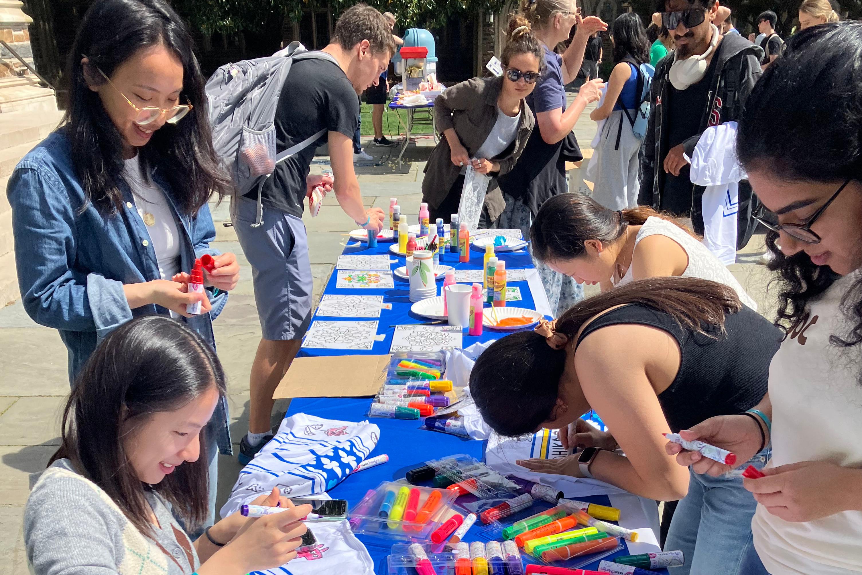 Students gathered around a table outside color t-shirts.
