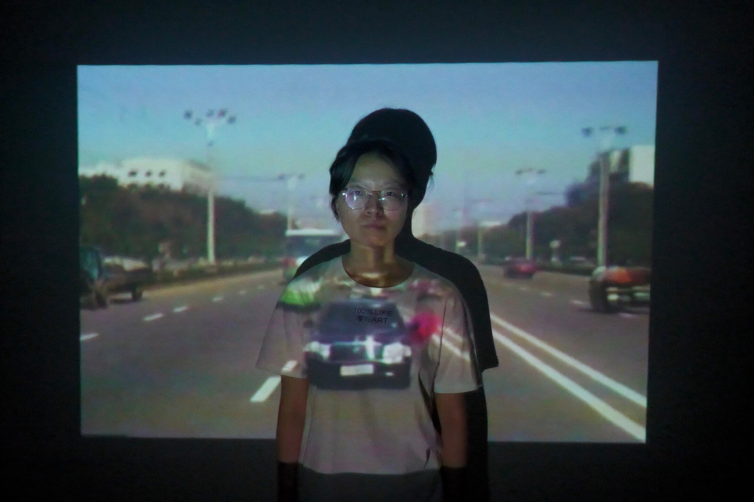 A person standing in front of a wall or screen onto which a film is being projected