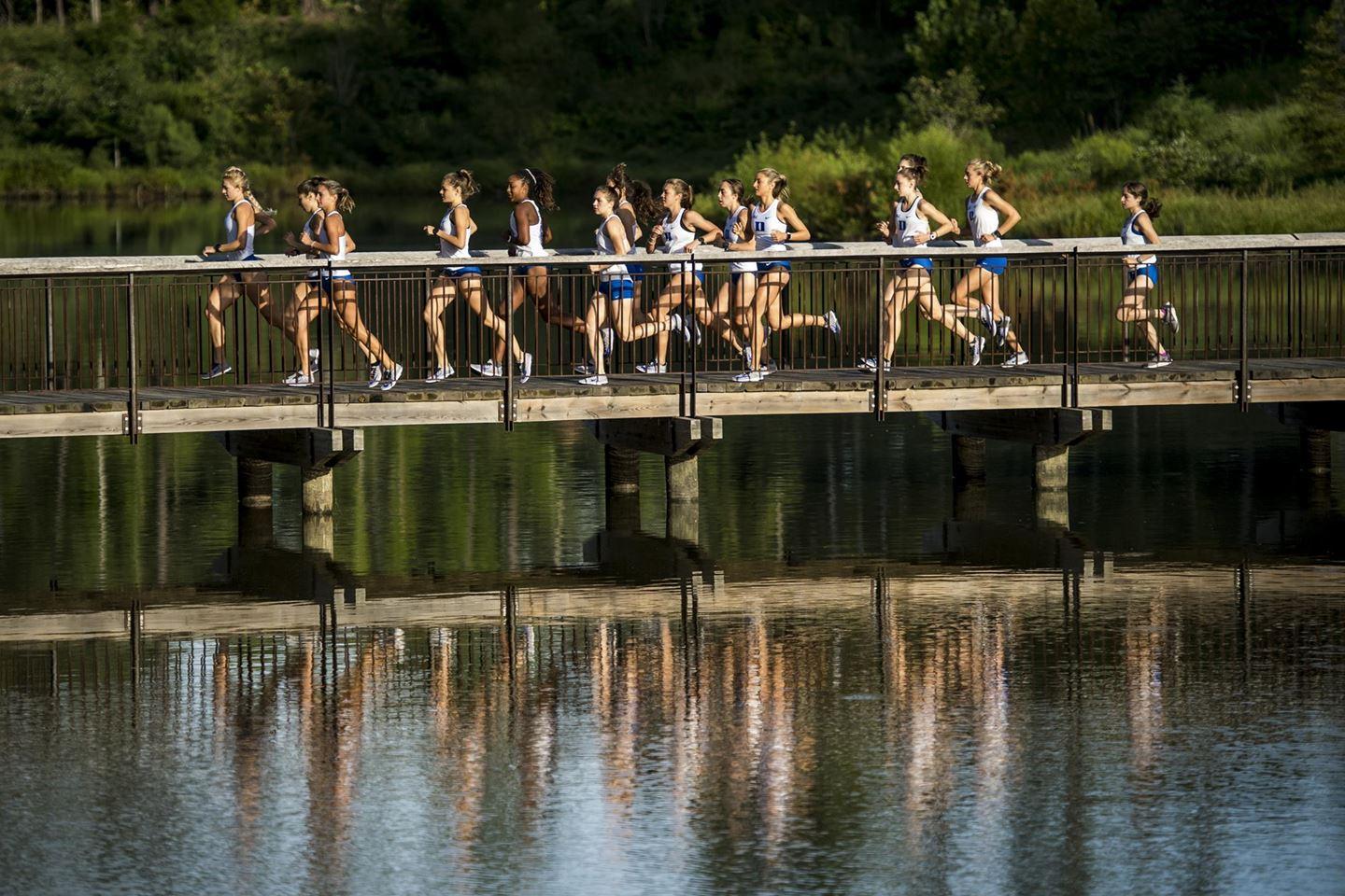 Duke runners on bridge reflected in water