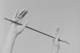 Still from Katelyn Auger's 'Paradise in the Pines' depicting 2 upraised hands holding an arrow