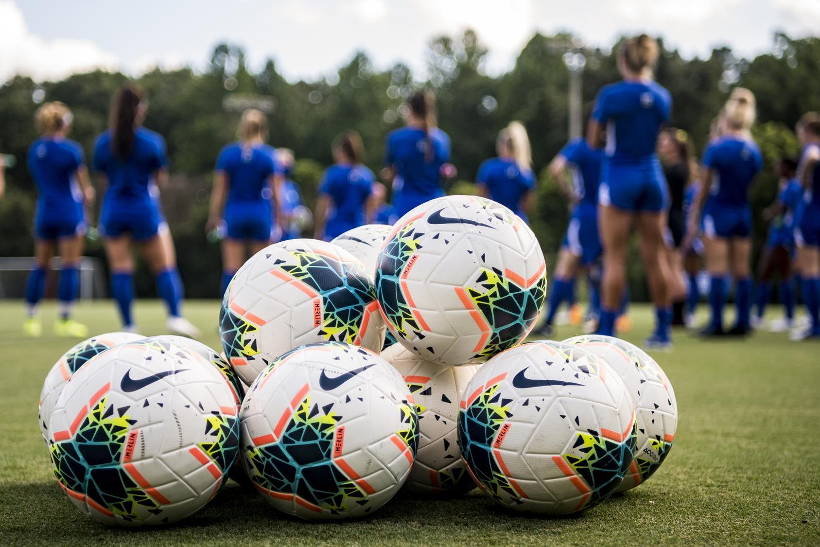 soccer practice with mound of soccer balls in foreground