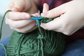 Hands holding knitting needles and yarn making a stitch Hands holding knitting needles and yarn making a stitch