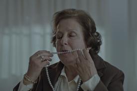 An upper-class older woman sensuously holds a pearl necklace up to her lips, in a scene from &amp;amp;amp;quot;Destello Bravío&amp;amp;amp;quot;.