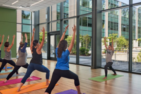 People standing in forward lunges, arms up, on yoga mats People standing in forward lunges, arms up, on yoga mats
