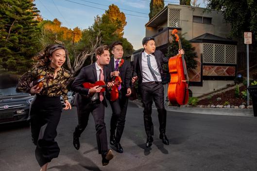 Amusing photo of the four musicians running down a city street with their instruments