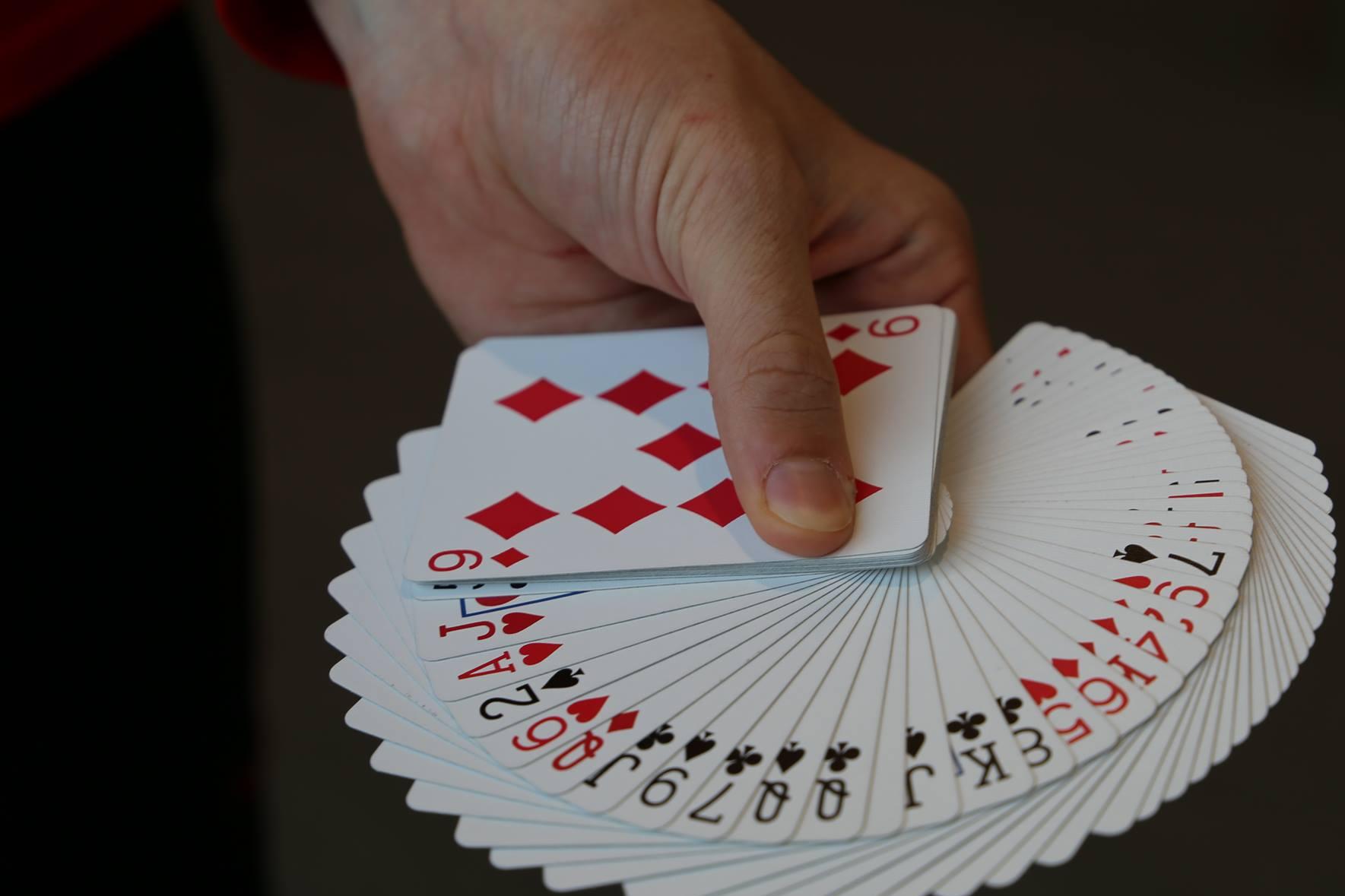 hand holding a deck of cards spread out showing each suit hand holding a deck of cards spread out showing each suit