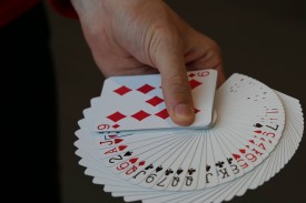 hand holding a deck of cards spread out showing each suit hand holding a deck of cards spread out showing each suit