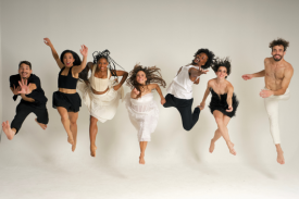 5 dancers jump towards the camera in front of a white background.
