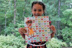 A young visitors holds up the picture she made at Family Day.