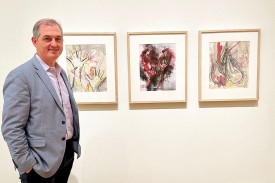 Dr. Joe Turek poses near prints by artist Carolee Schneeman