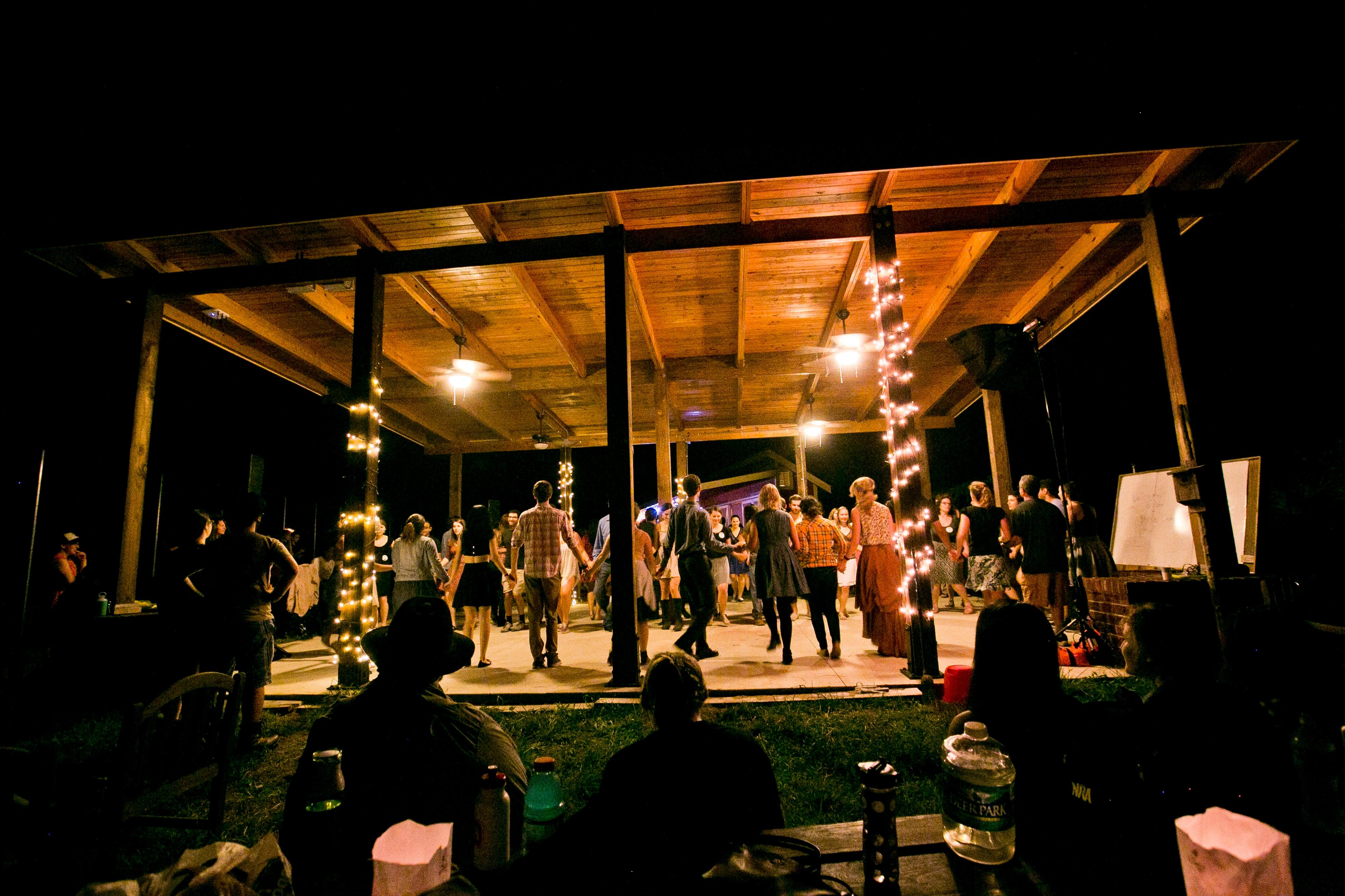 people dancing at night under lit pavilion