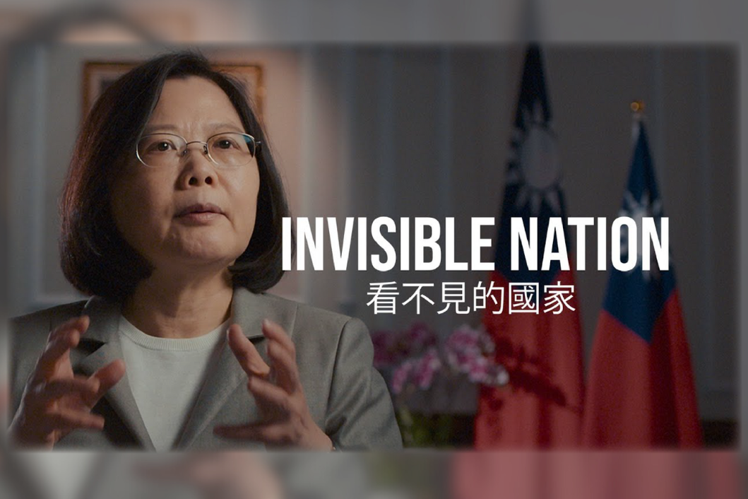 Portrait photo of Tsai-Ing Wen in a gray jacket with raised hands; background: blooming orchids and two Taiwanese flags; text: &amp;quot;Invisible Nation&amp;quot; (看不見的國家)