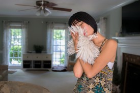 color photograph of a teenage girl inside a house who is holding fur to her face