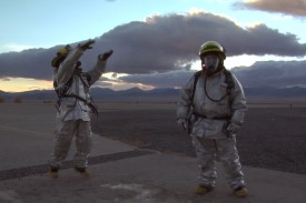 Film still showing basketball pickup game during down-time between workers wearing full protective suits for hazardous conditions