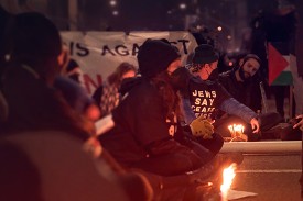 image of protesters at a protest with one person wearing a t-shirt that says "Jews say ceasefire now"