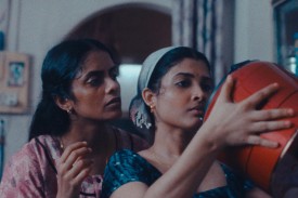 Two women look into an orange bucket in a still from All We Imagine As Light