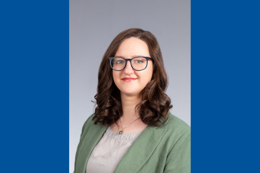 Seminar speaker, Ilaria Merutka, smiling, wearing glasses and a green blazer