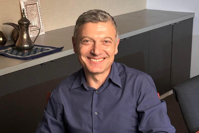 headshot of smiling man in blue shirt